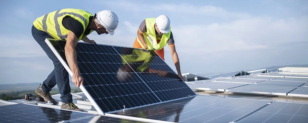 Team von zwei Ingenieuren, die Sonnenkollektoren auf dem Dach installieren.