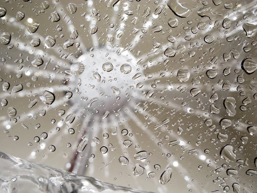Wassertropfen aus einem Duschkopfs auf einer Glasscheibe