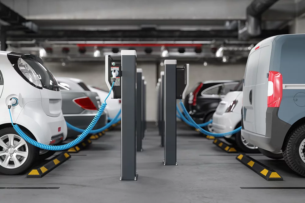 Abbildung einer Garage mit sechs E-Autos, die alle über Ladesäulen aufgeladen werden. Symbolbild für Elektromobilität.
