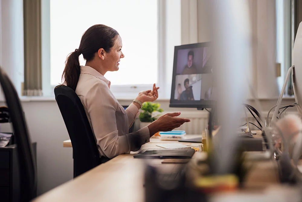 Eine Frau befindet sich in einem Video Konferenz Call einer virtuellen Eigentümerversammlung.