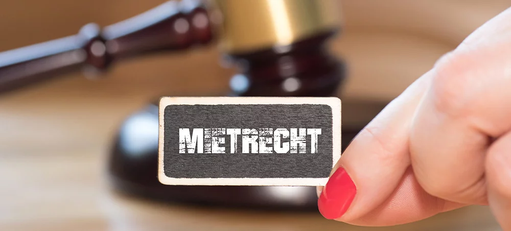 Ein Richterhammer und eine Hand, die ein Schild hält, auf dem 